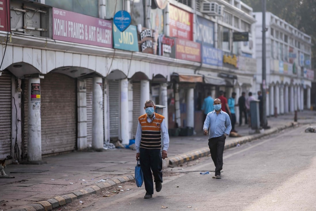 People wearing face masks as a preventive measure against the Covid-19 novel coronavirus walk past closed shops in a market area in New Delhi on March 23, 2020. Photo: AFP