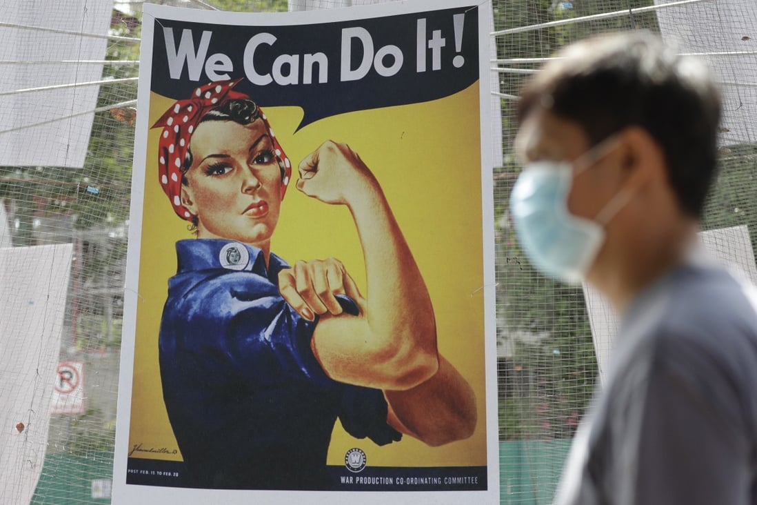 A man wearing a protective mask walks beside a poster of American WWII icon Rosie the Riveter at the Quezon city hall in the Philippines. Photo: AP