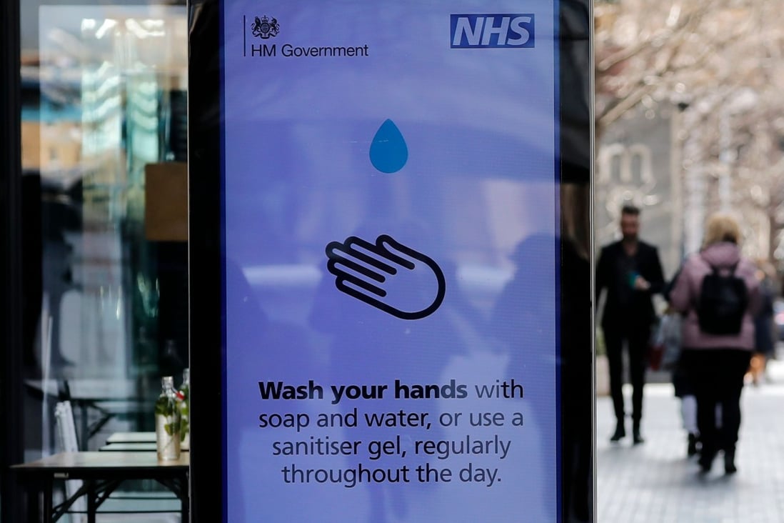 People walk past a sign in London giving public information the coronavirus outbreak. Photo: AFP