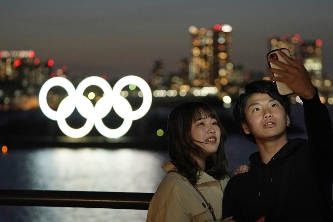 A couple take a selfie with the giant Olympic rings monument in the background at Odaiba Marine Park in Tokyo. Photo: EPA