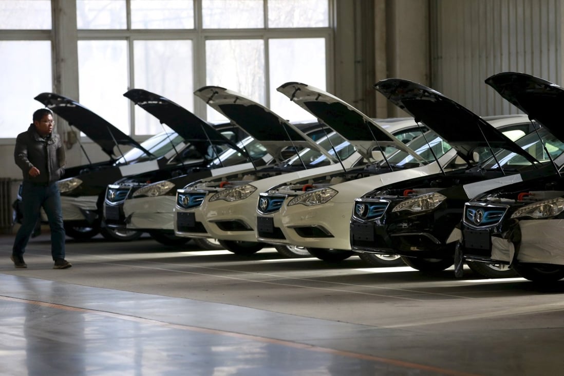 A man walks past cars at an assembly line producing electronic cars at a factory of Beijing Electric Vehicle, funded by BAIC Group, in Beijing, China. Photo: Reuters