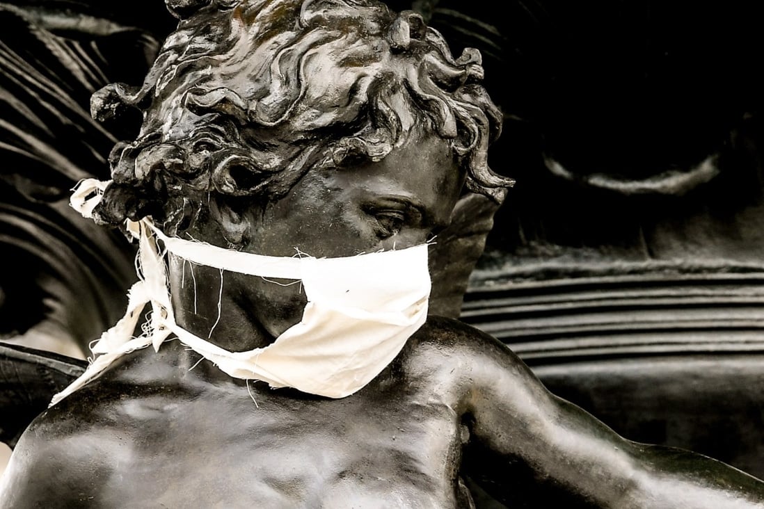 A bronze statue is decorated with a face mask in central Dresden, Germany. The German government and local authorities are heightening measures to stem the spread of the coronavirus which causes the Covid-19 disease. Photo: EPA