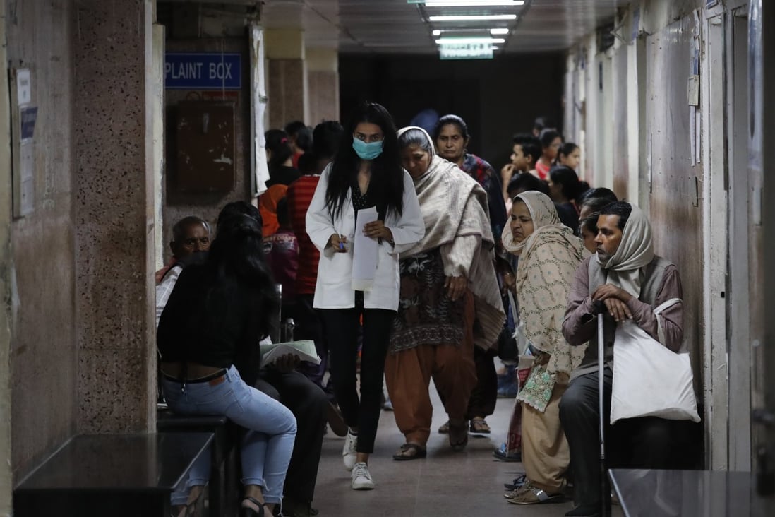 A doctor walks past patients waiting to be examined for fever and other aliments at a government-run hospital in New Delhi, India. Photo: AP