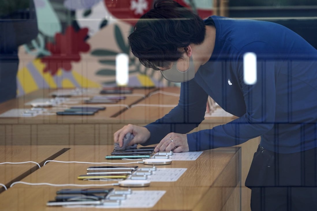 An Apple Store employee wearing a protective mask cleans the screen of an iPhone inside the US technology giant’s store in the Omotesando area of Tokyo, Japan, on March 15. Photo: Bloomberg