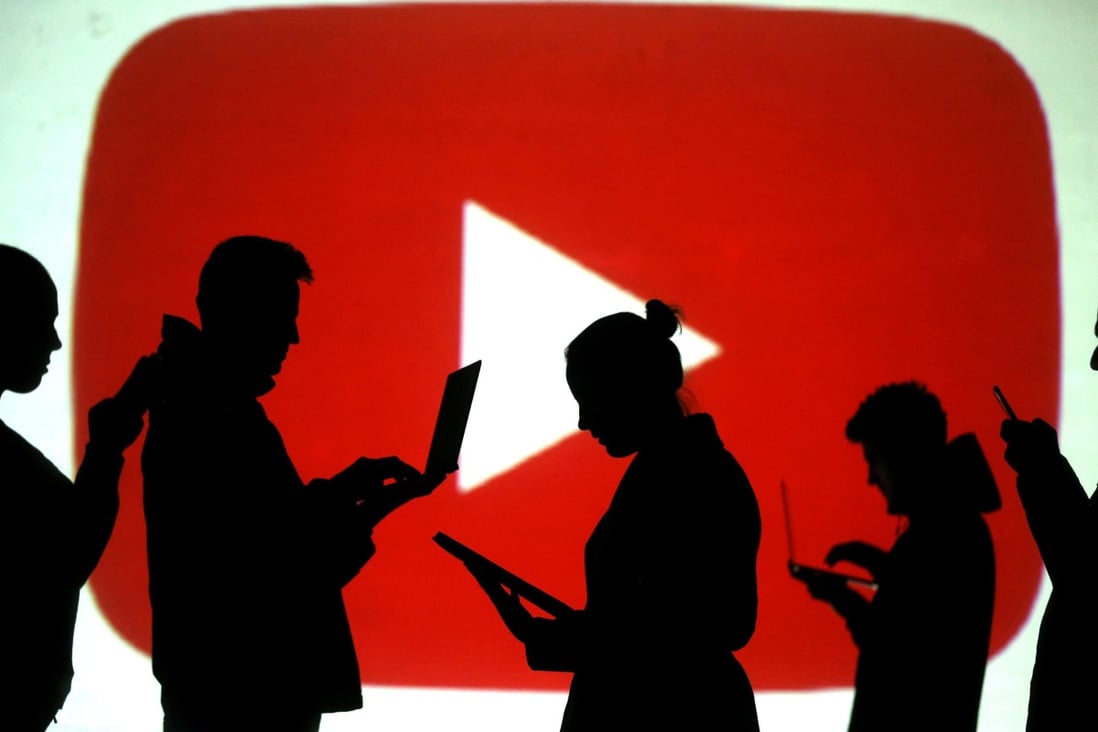Silhouettes of laptop and mobile device users are seen next to a screen projection of YouTube’s logo in this picture illustration. Photo: Reuters/Dado Ruvic