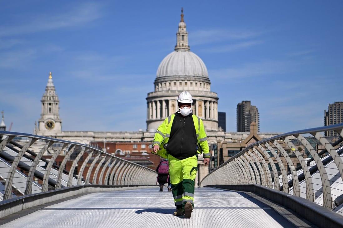 A construction worker crosses the Millennium Bridge in London, Britain. Photo: EPA