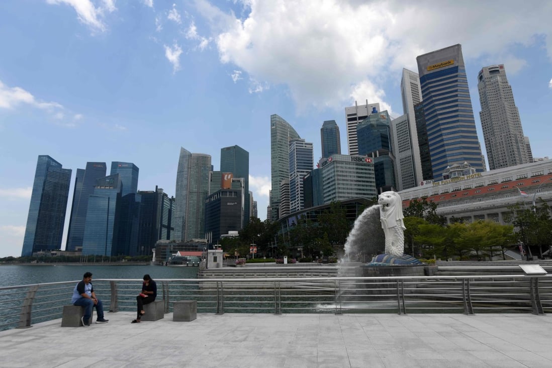 People sit near the Merlion statue in Singapore. Although the government has won praise for its handling of the coronavirus outbreak, a lockdown is looking increasingly likely as cases continue to rise. Photo: AFP