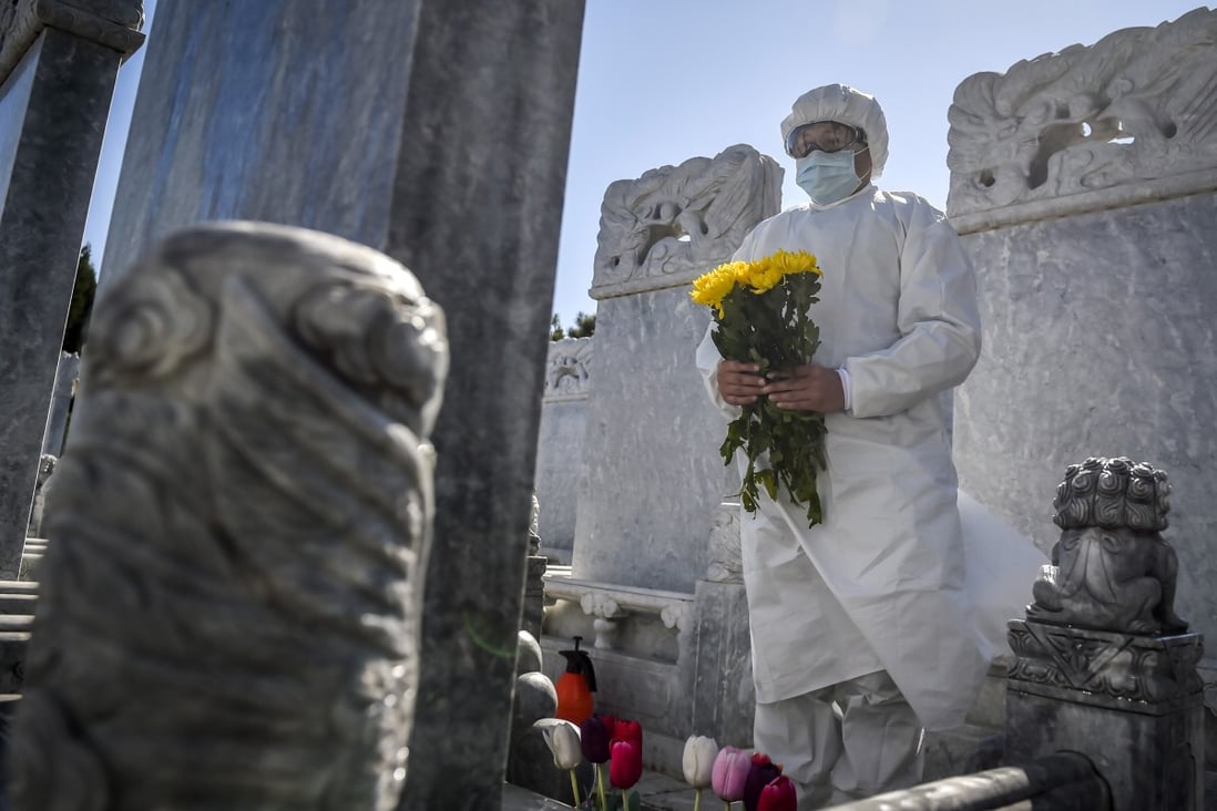 A cemetery worker in a protective suit makes an offering of flowers at a gravesite in the Babaoshan cemetery in Beijing. Photo: AP
