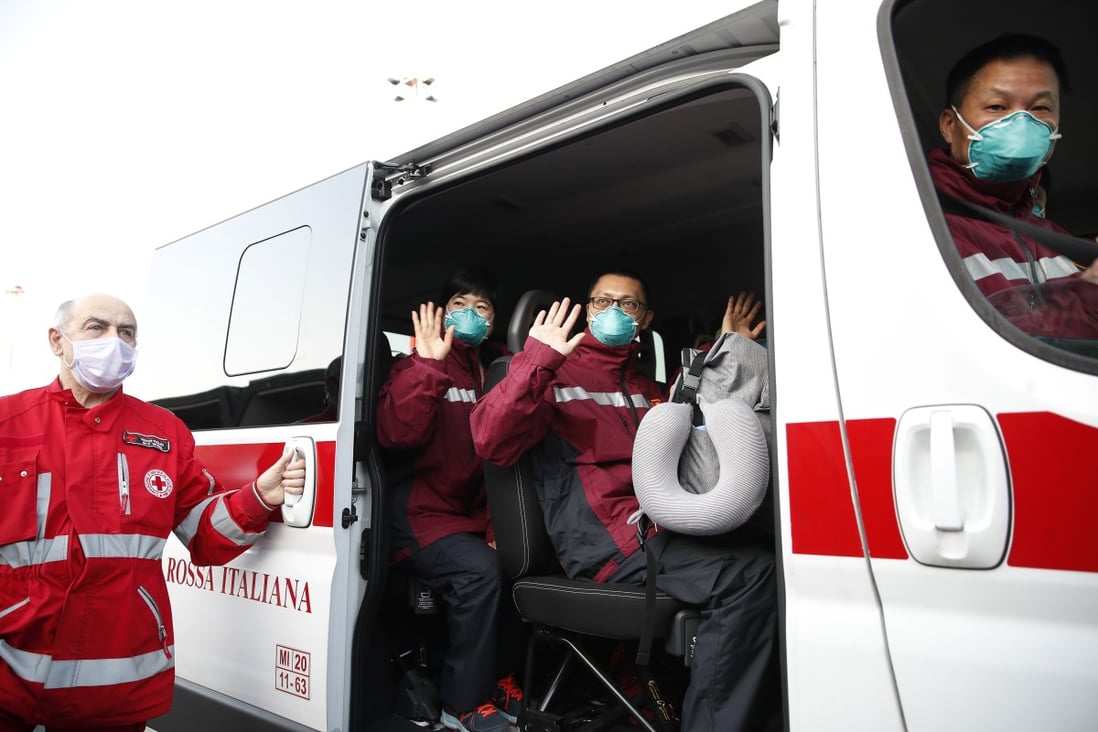 Doctors and paramedics from China wave on a Red Cross vehicle after arriving at Malpensa airport, Milan, on March 18, part of a team of 37 and a shipment of 20,000 tonnes of equipment sent to help Italy. Photo: AP