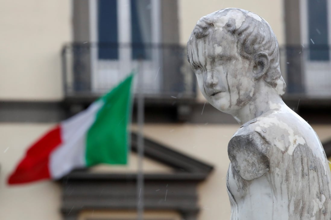 A statue on the Fountain of Neptune is seen in front of an Italian flag in Naples on Sunday. Photo: Reuters