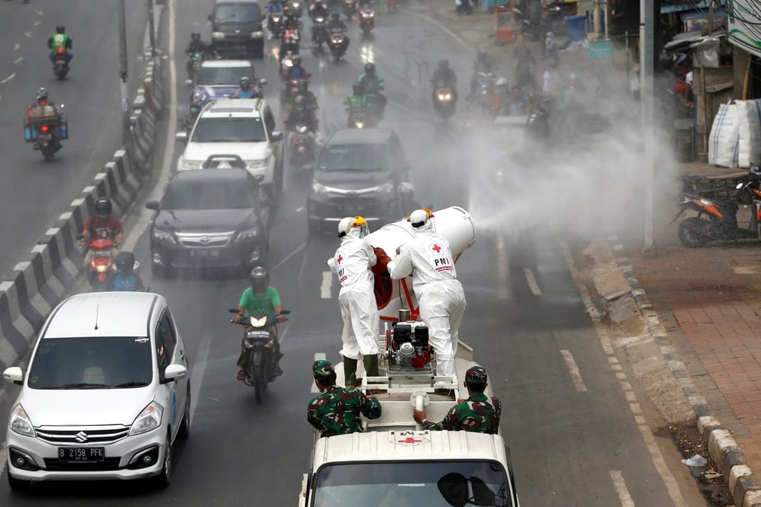 Indonesian Red Cross personnel in Jakarta spray disinfectant on the road to prevent the spread of the coronavirus. Photo: Reuters