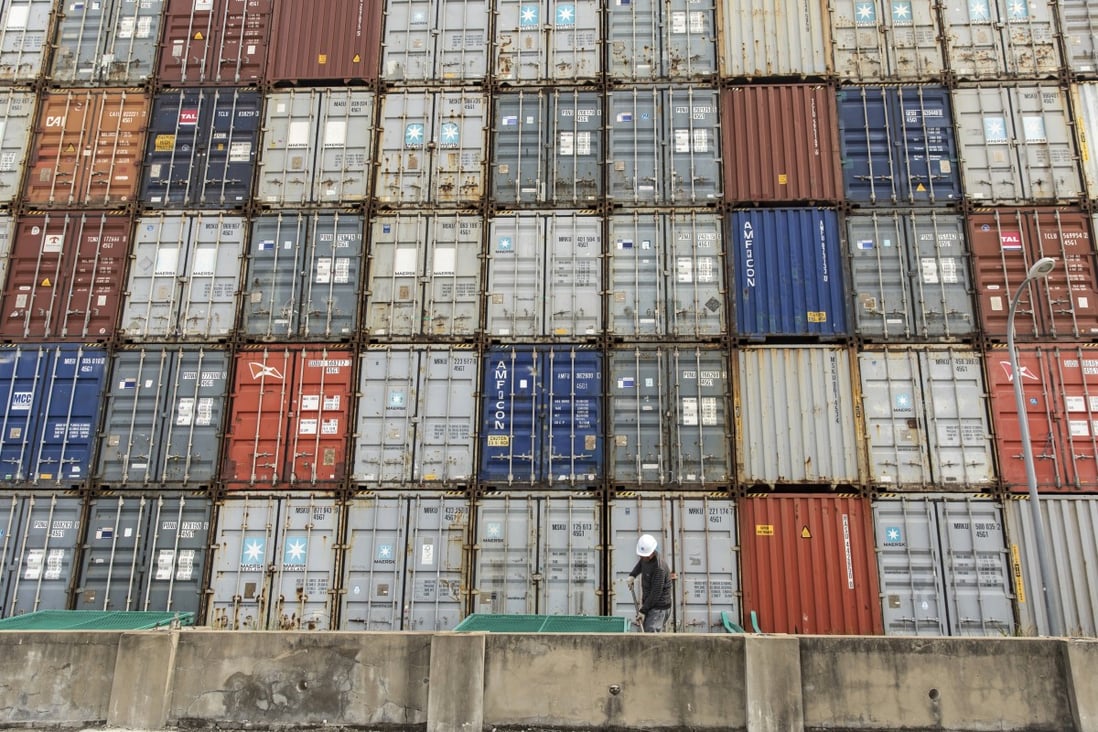 A worker uses a shovel in front of stacked shipping containers at the Yangshan Deepwater Port in Shanghai, China, on Monday, March 23, 2020. Photo: Bloomberg