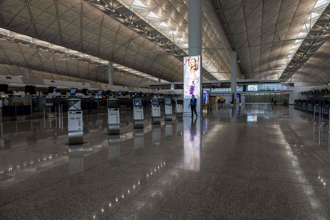 A worker wearing a face mask walks past closed check-in counters at Hong Kong International Airport. Photo: AFP