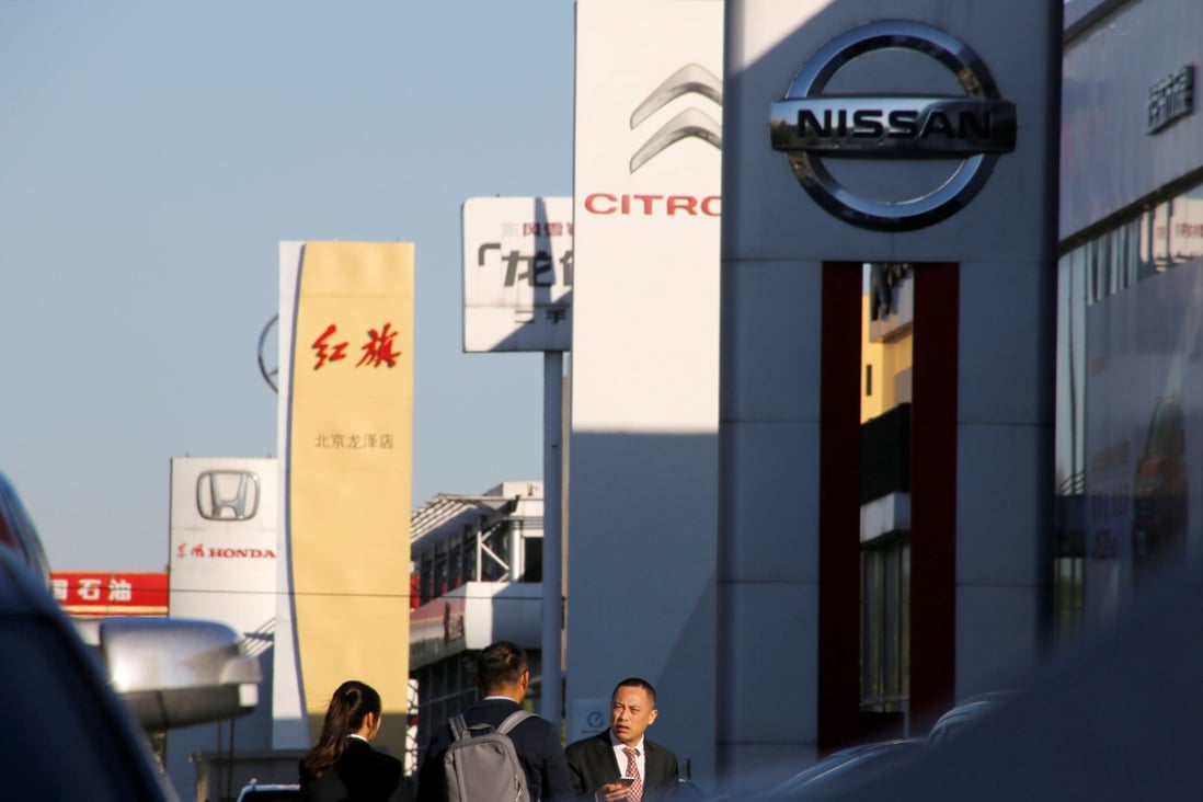 People walk near the showrooms of Chinese and foreign car dealerships in Beijing. China’s auto industry has been hit hard by the coronavirus. Photo: Reuters