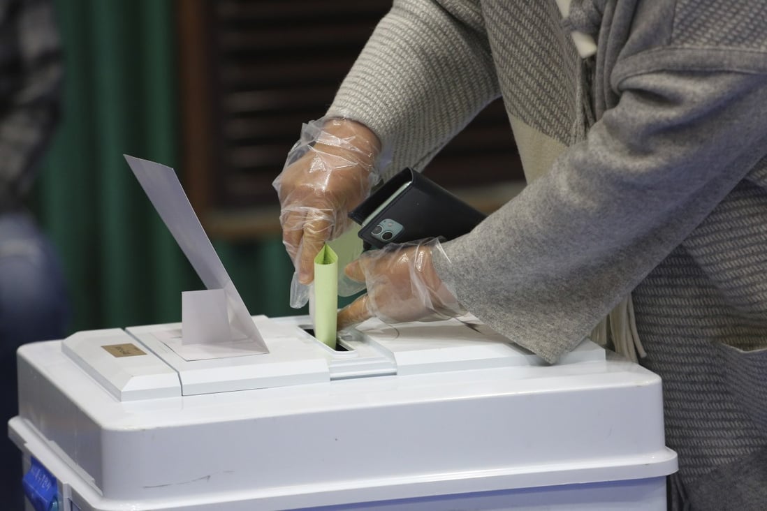A voter wearing plastic gloves casts a vote at a polling station in Seoul on Wednesday. Photo: AP