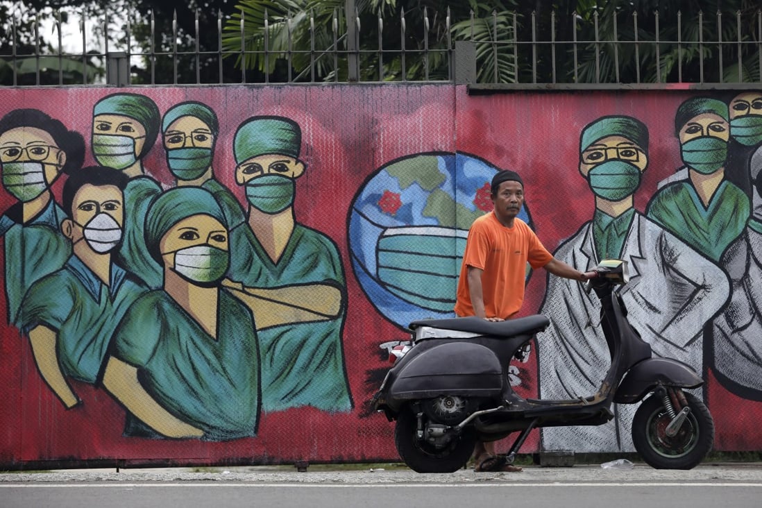 A motorist stops near a mural painted as a tribute to medical workers on the outskirts of Jakarta. Photo: AP
