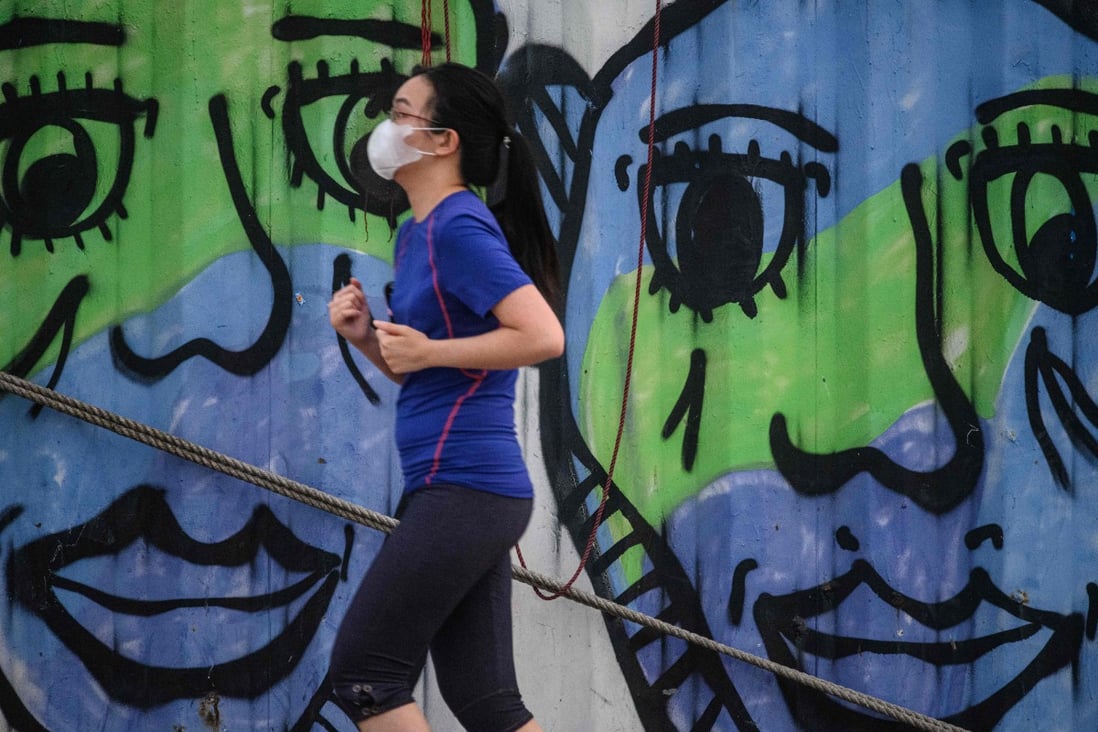 A woman wears a face mask she jogs along a cargo dock in Hong Kong. Photo: AFP