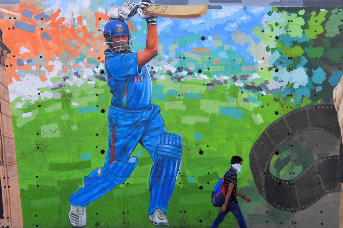 A man wearing a face mask walks past a mural of Indian cricketing legend Sachin Tendulkar in Mumbai on March 19. India’s 700-million-strong youth population could provide a ready talent pool for the provision of services internationally. Photo: AFP