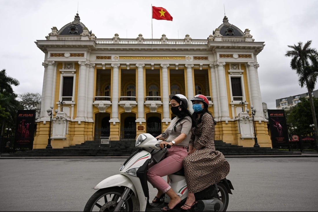 Women wearing face masks ride past the Opera House in Hanoi. The Vietnamese government says it was not behind a cyberattack on Chinese state organisations to obtain coronavirus information. Photo: AFP