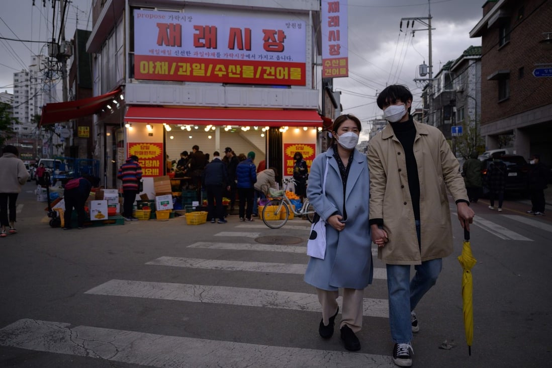 A couple wearing face masks amid concerns over the COVID-19 novel coronavirus walks through a market in Seoul on April 22, 2020. Photo: Agence France-Presse