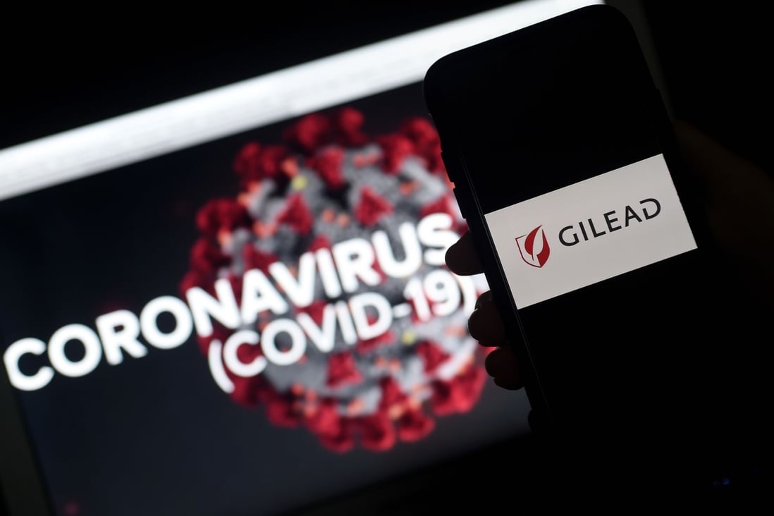 Gilead’s logo is displayed on a smartphone next to a screen showing a coronavirus graphic on March 25, 2020 in Arlington, Virginia. Photo: AFP