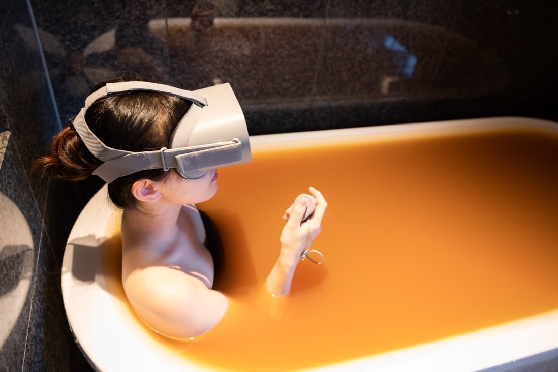An employee of Arima Onsen tries out the new virtual reality experience while posing in a bathtub filled with water from a hot spring. Photo: Handout