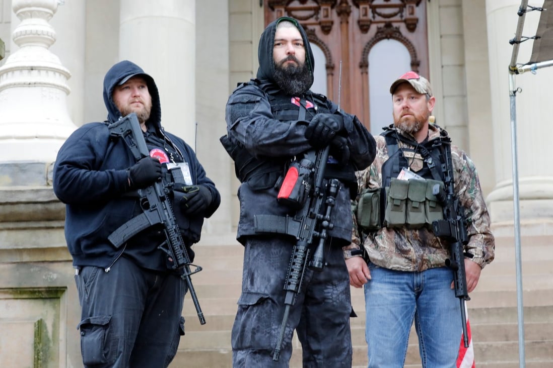 Armed protesters provide ‘security’ on the steps of the Michigan State Capitol in Lansing, demanding the reopening of businesses. Photo: AFP