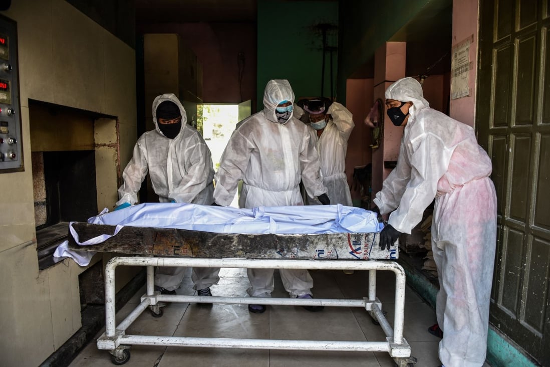 Personnel in protective suits prepare to move a body inside the crematory chambers at a crematorium facility in Manila. Photo: AFP