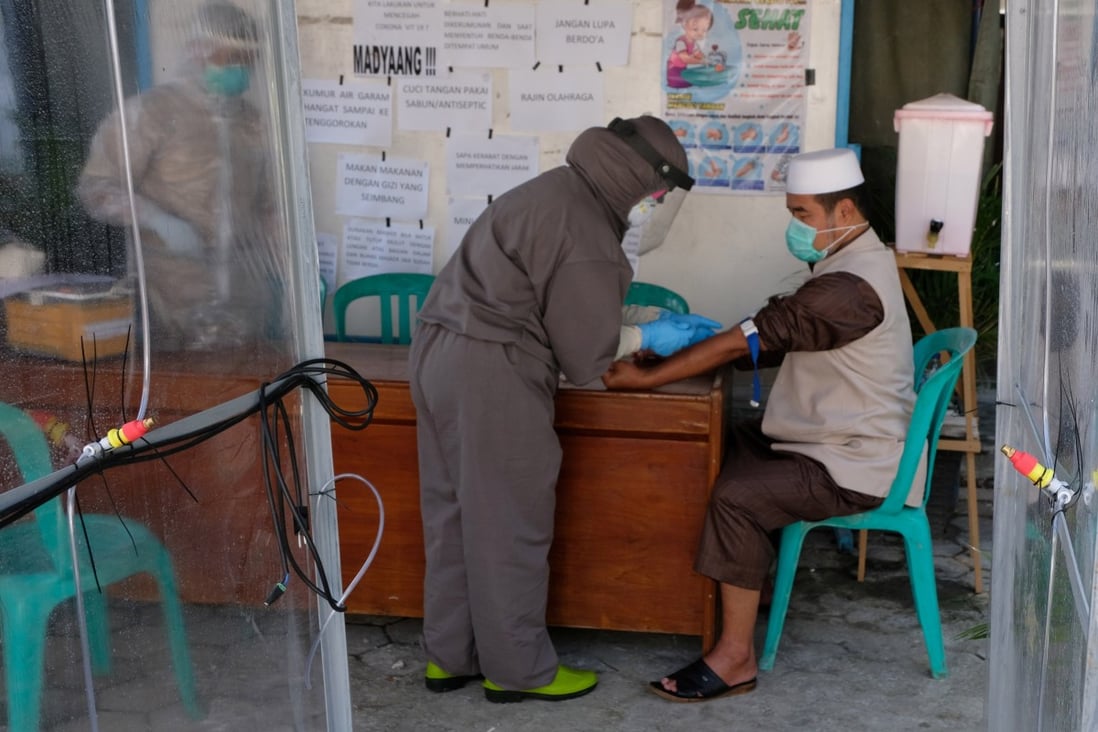 Medical staff wearing protective gear takes a blood sample from a Tablighi Jamaat member in Central Java Province, Indonesia, on April 20. Photo: Reuters