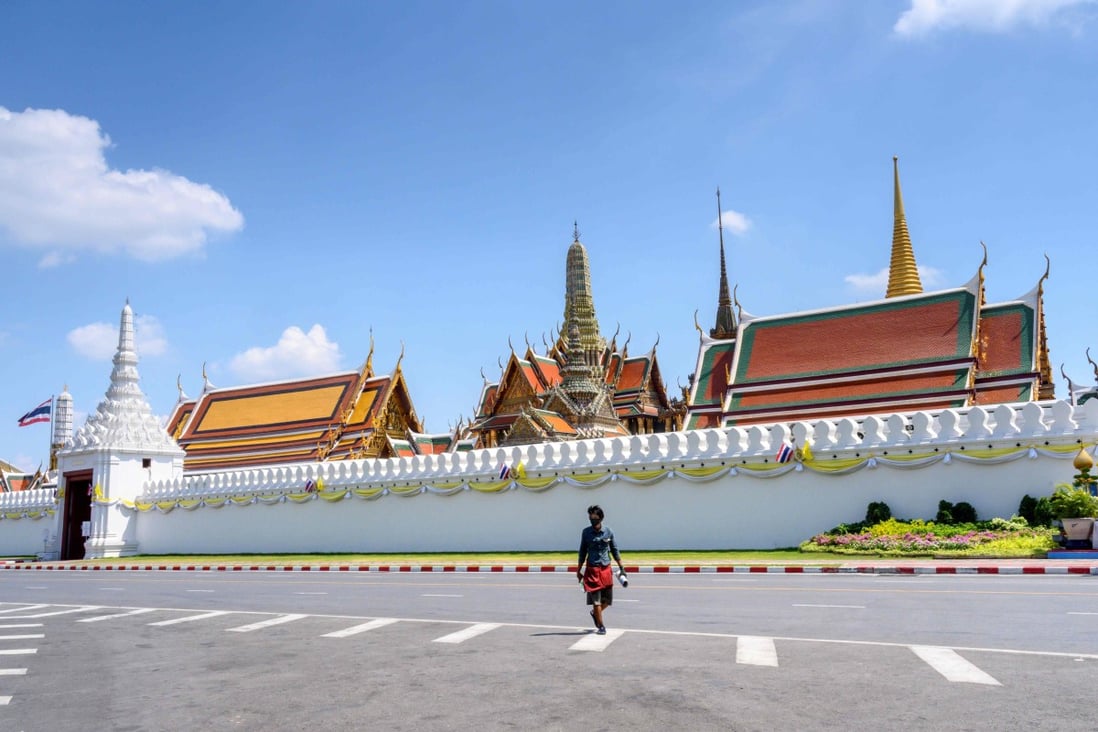 A man, wearing a facemask amid concerns about the spread of Covid-19, crosses a deserted street in front of the Grand Palace in Bangkok. Photo: AFP