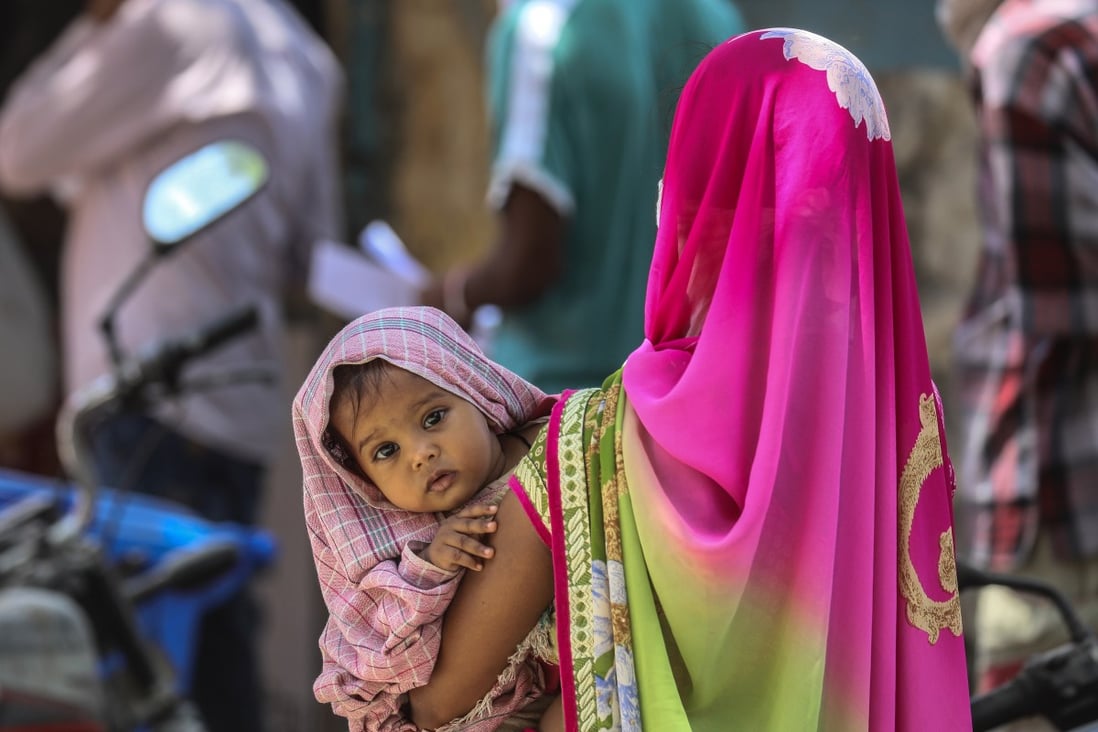 A woman holds a child as she stands in a queue in Mumbai amid India’s coronavirus lockdown. Photo: EPA