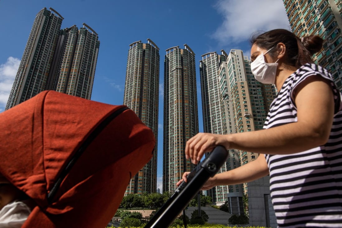 A woman wearing a face mask pushes a baby stroller past residential buildings near West Kowloon station in Hong Kong on Wednesday. Photo: Bloomberg