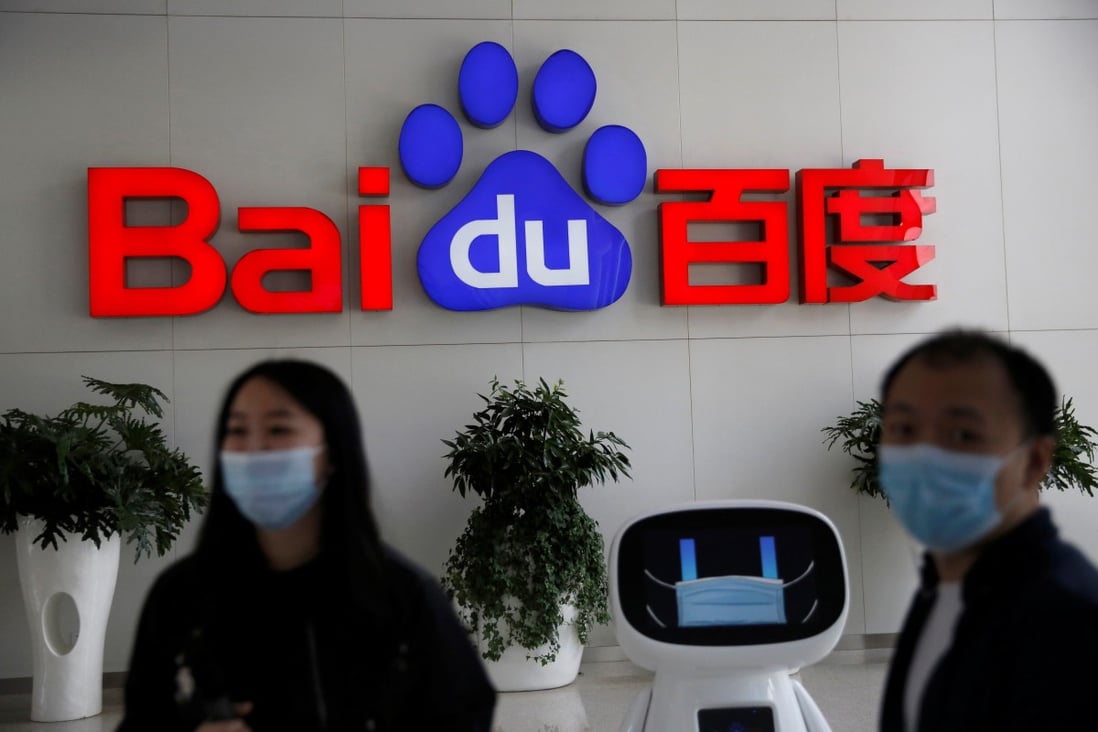 Baidu employees wearing face masks are seen next to the company’s artificial intelligence robot at the Chinese internet search giant’s headquarters in Beijing on May 18. Photo: Reuters
