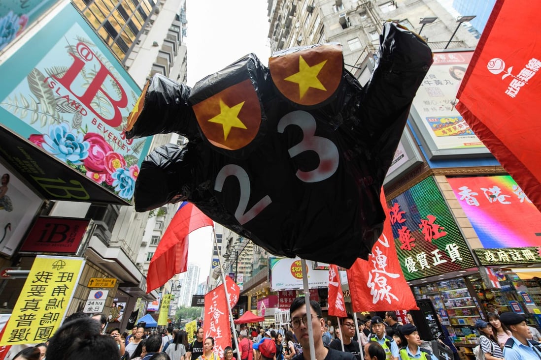 A figure in the shape of a hand with the colours of the Chinese national flag for fingernails and a '23' on its palm in reference to Article 23 is carried by protesters at a National Day rally in Hong Kong in 2018. Photo: AFP