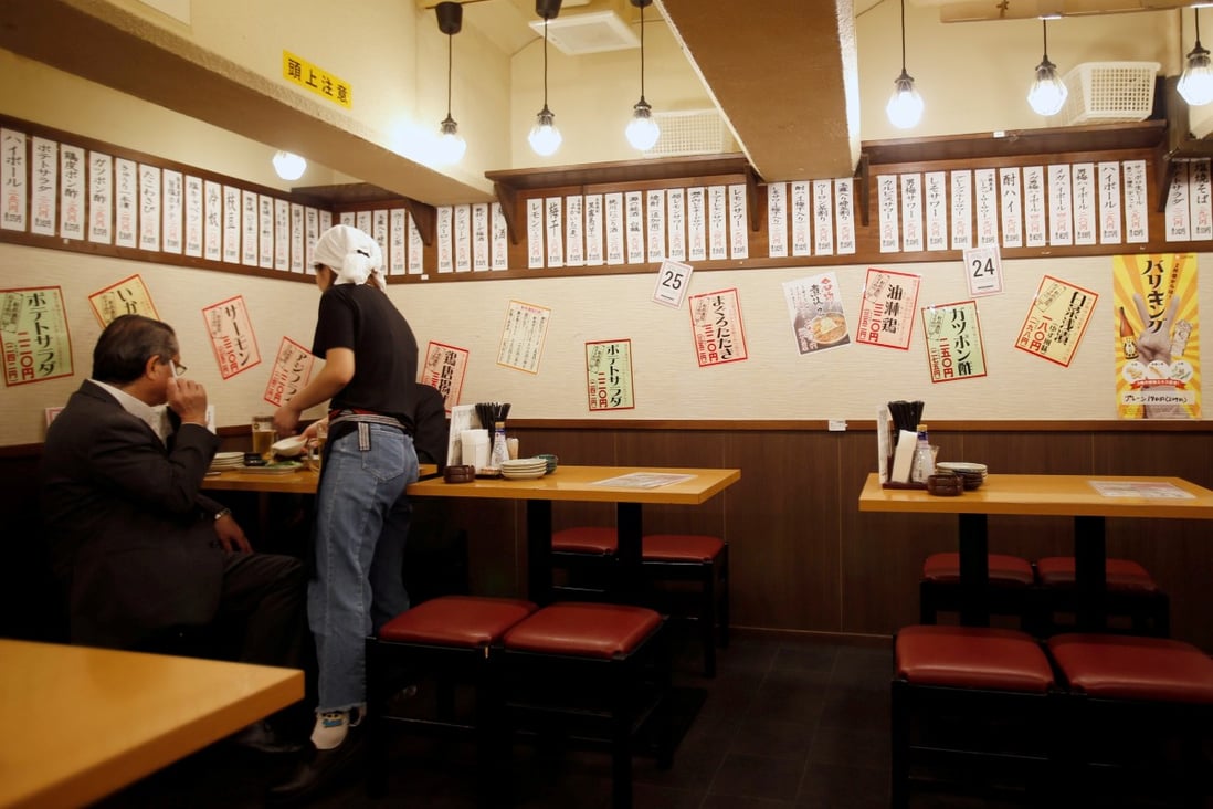 A Tokyo office worker is seen at a discount izakaya bar offering cheap food and drinks. Some establishments were targeted before Japan lifted its emergency restrictions. Photo: Reuters