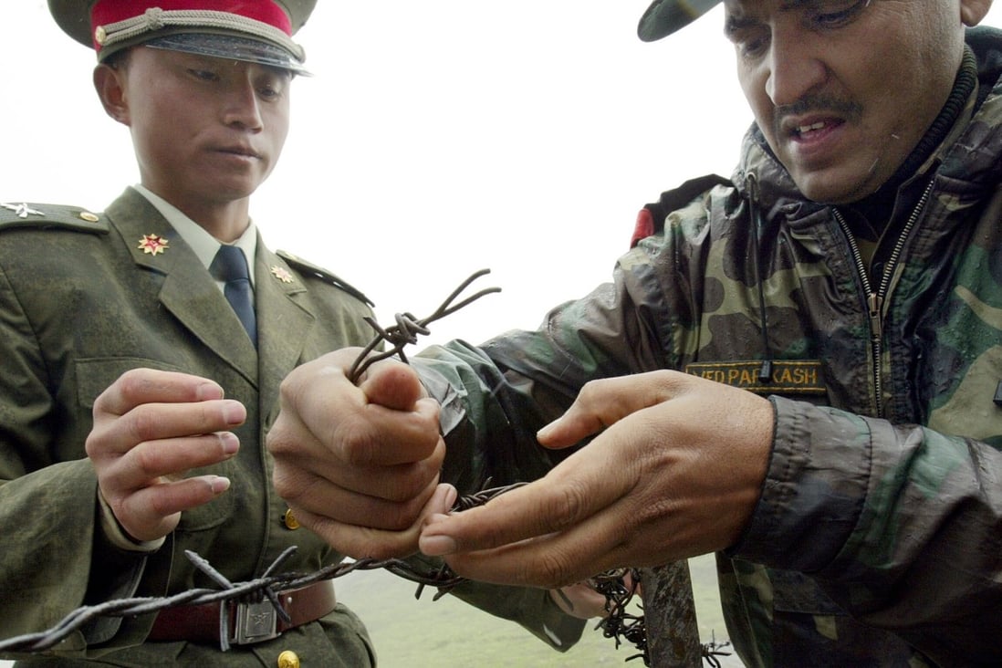 A Chinese soldier and an Indian soldier work on a wire fence near their shared border. Photo: AFP