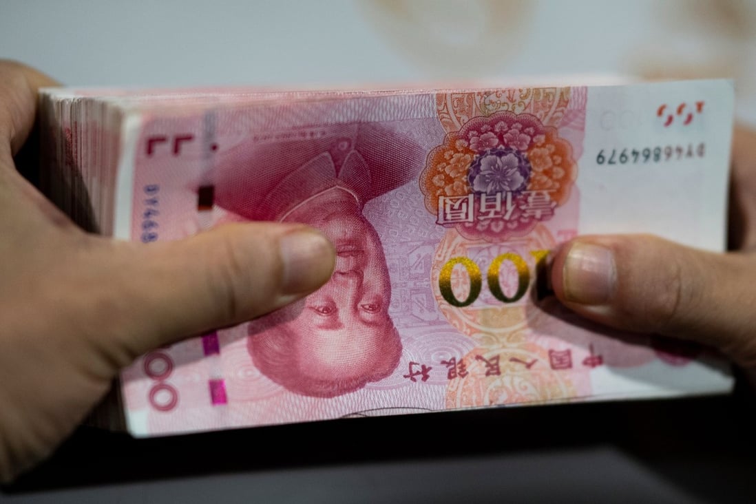 A bank employee counts 100-yuan notes at a bank in Shanghai. Photo: AFP