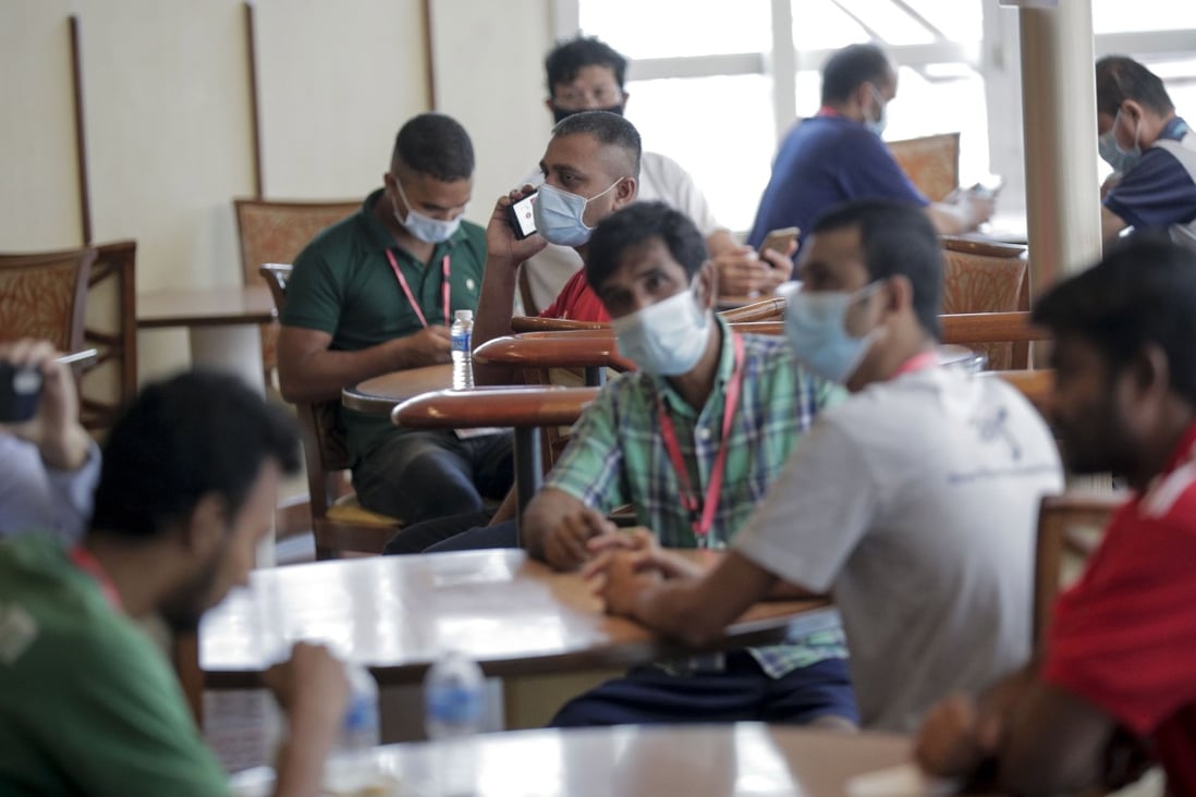 Migrant workers sit in a dining area aboard a cruise ship being used to house those who have recovered from Covid-19. Photo: EPA