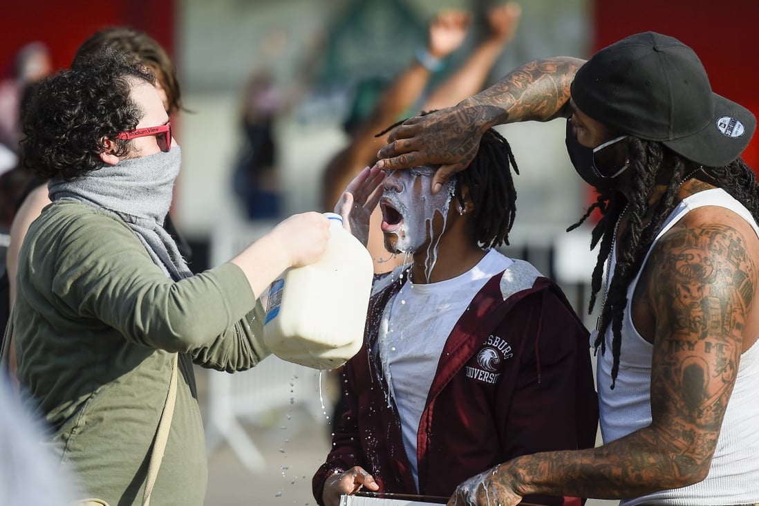 Protesters use milk to clear their eyes after being tear gassed by police in Minneapolis. Photo: EPA-EFE