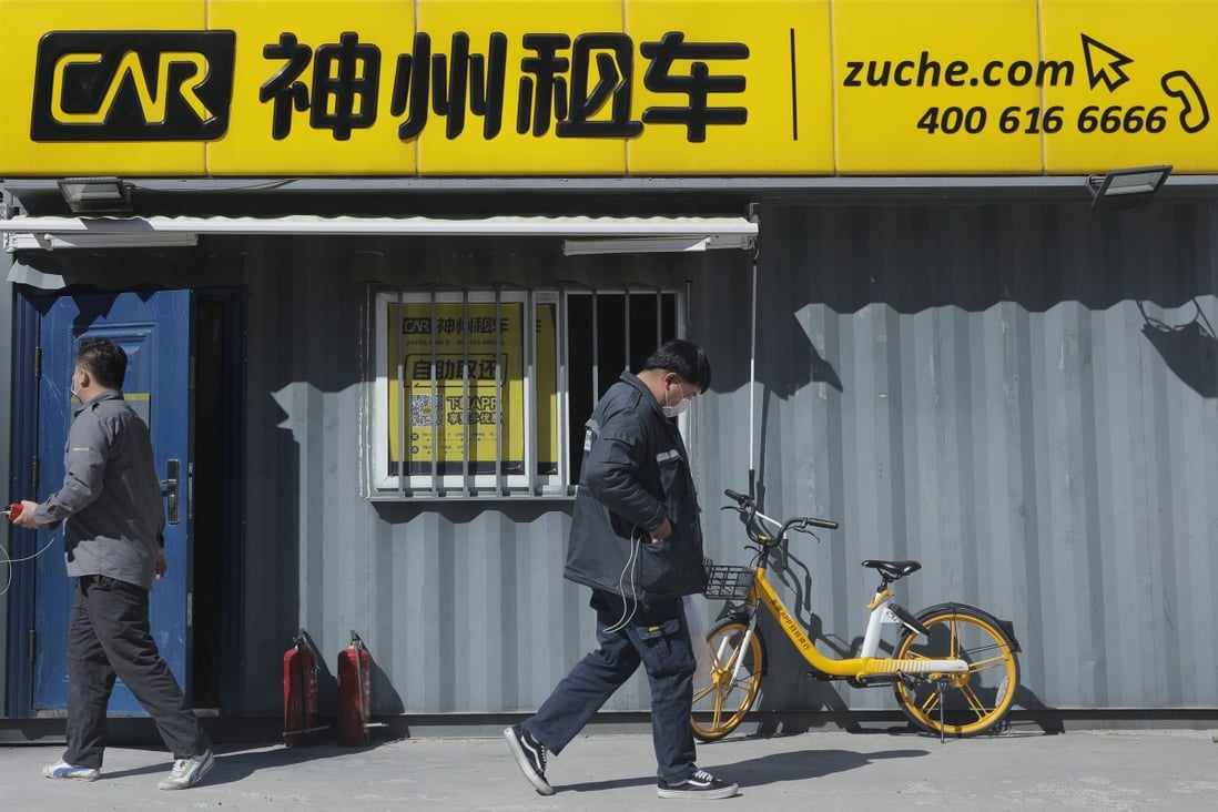 Employees walk pass by a chain of Shenzhou Zuche, as Car Inc is known in mainland China. China's biggest car rental company's share price has tumbled by association with Luckin Coffee through their co-founder. Photo: EPA-EFE