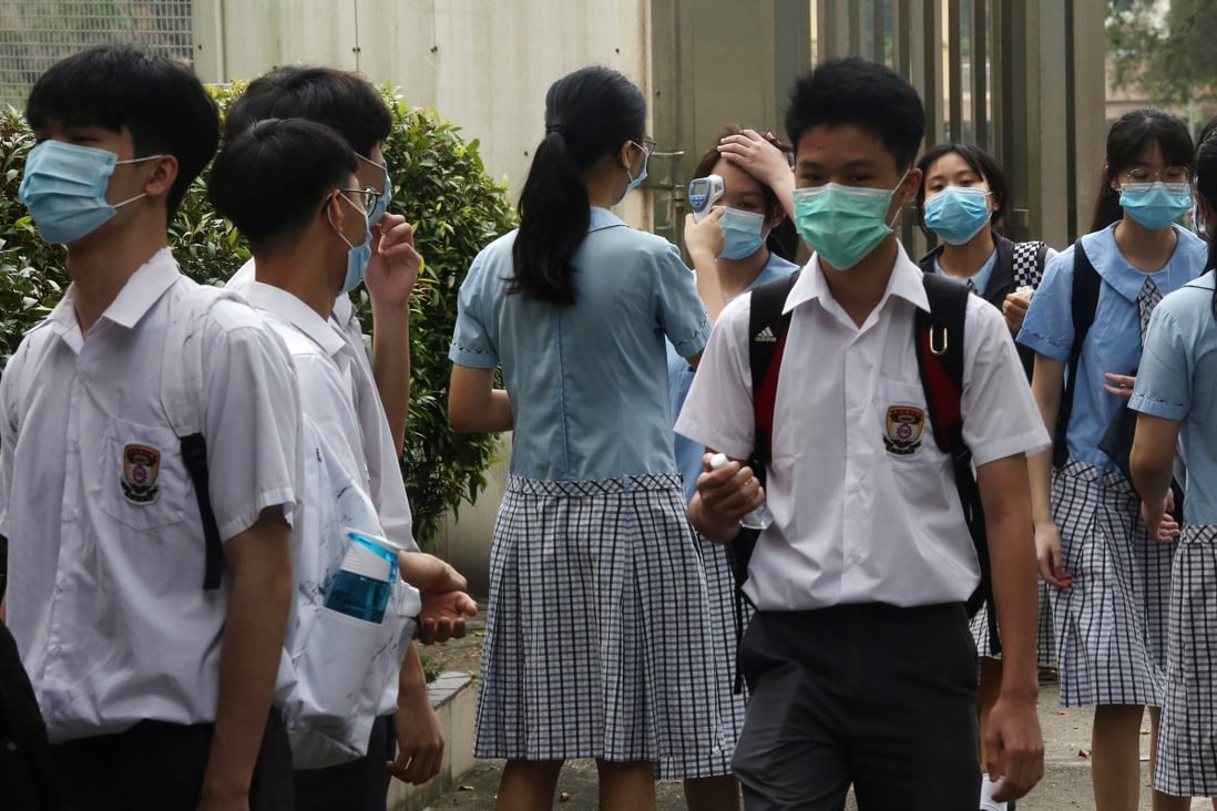 A student checks a peer’s temperature at the campus entrance, on the first day back to school after months of closure due to coronavirus-prevention measures, at a school in Shek Kip Mei on May 20. Photos: Jonathan Wong