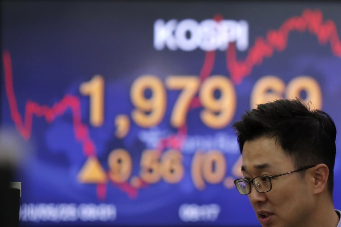 A currency trader walks past a screen showing the Korea Composite Stock Price Index in Seoul last month. Photo: AP