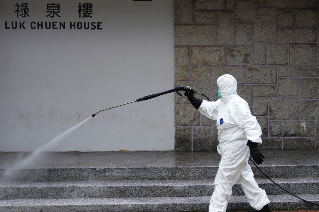 A worker in full protective gear disinfects Luk Chuen House at Lek Yuen Estate in Sha Tin. Photo: Sam Tsang