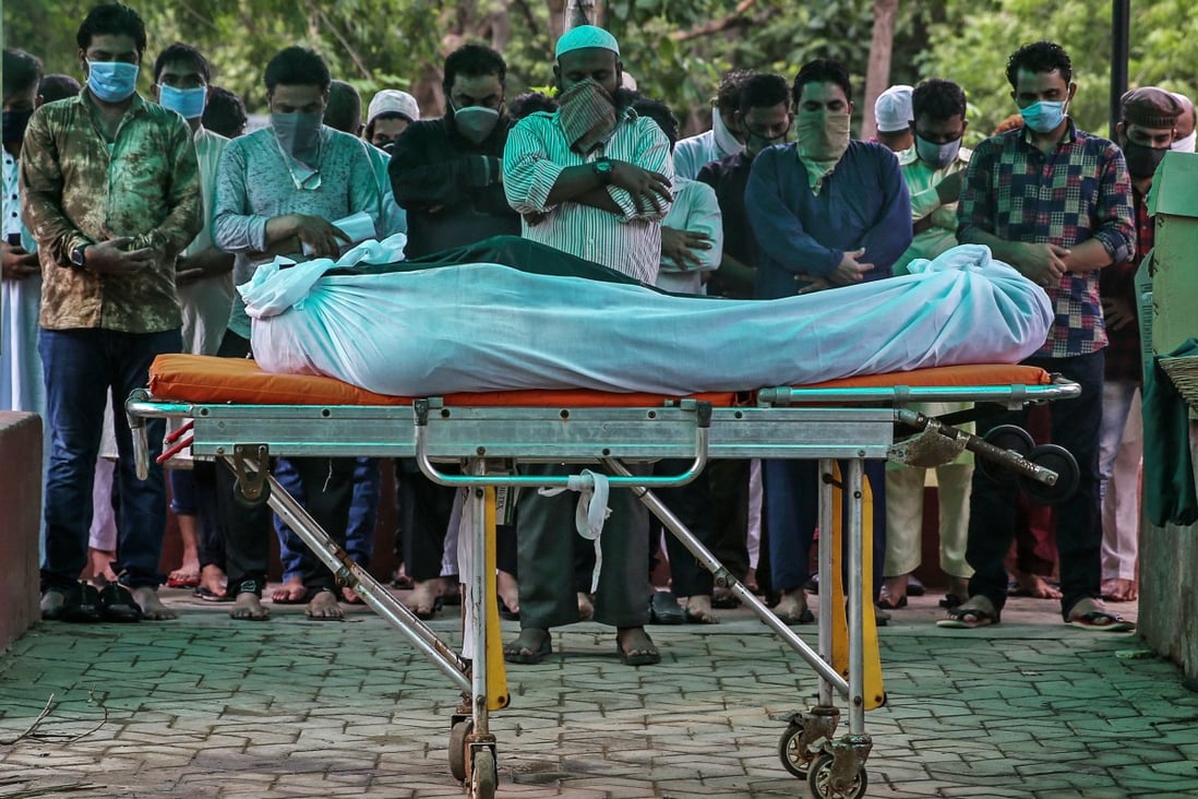 Relatives pray before the burial of a Covid-19 victim at Bada Qabrastan graveyard in Mumbai, India. Photo: EPA