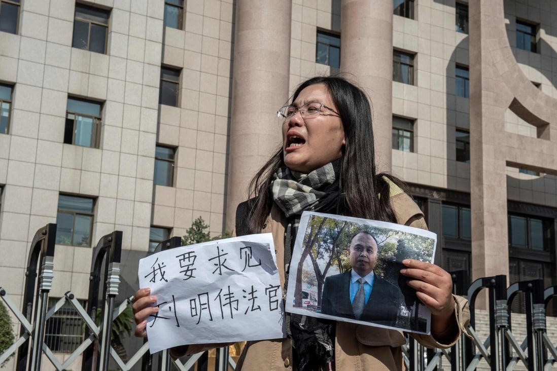 Xu Yan, wife of human rights lawyer Yu Wensheng, holds up his photo and a piece of paper that reads “I want to request a meeting with Judge Liu Mingwei”, outside the Intermediate People’s Court in Xuzhou on October 31, 2019. Yu, detained in Beijing in January 2018 after calling for multi-candidate elections, was sentenced to four years in prison on June 17 after a secret trial found him guilty of inciting subversion of state power, his wife said. Photo: AFP