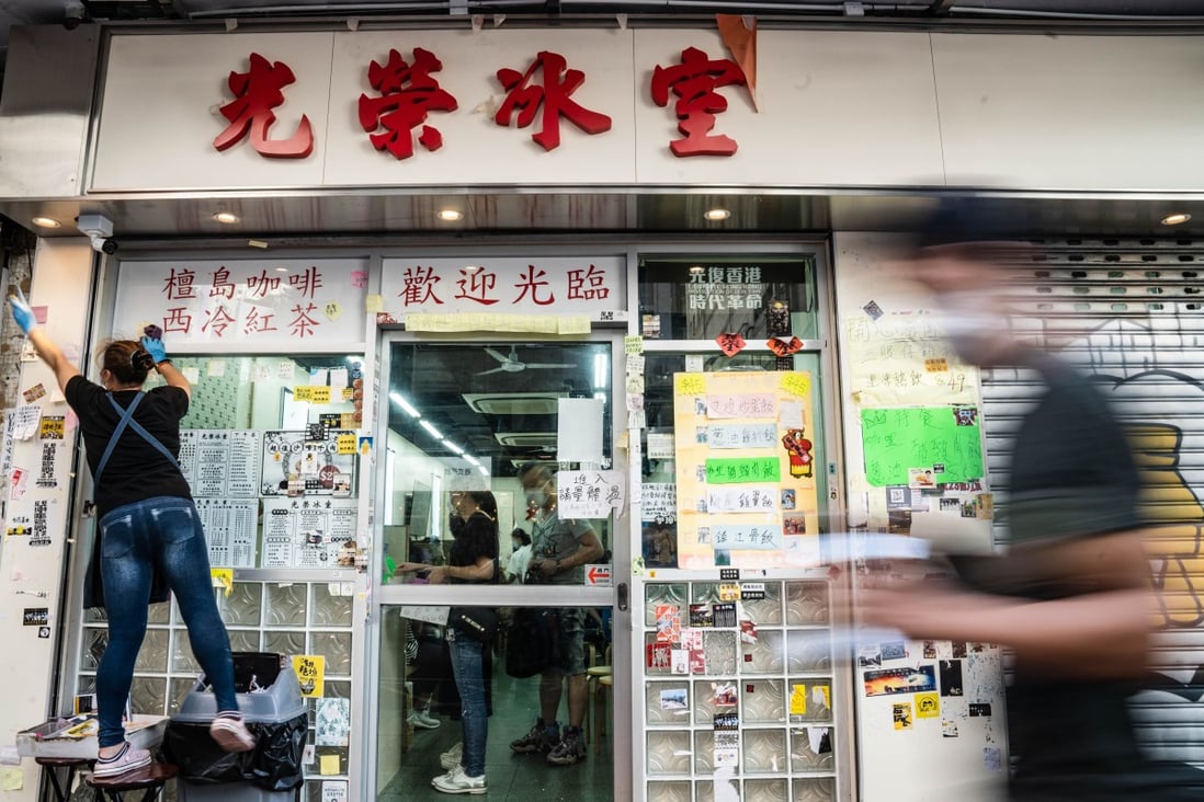 An employee scrapes off stickers and posters with messages in support of the protest movement on a wall outside a restaurant in Hong Kong. Photo: Bloomberg
