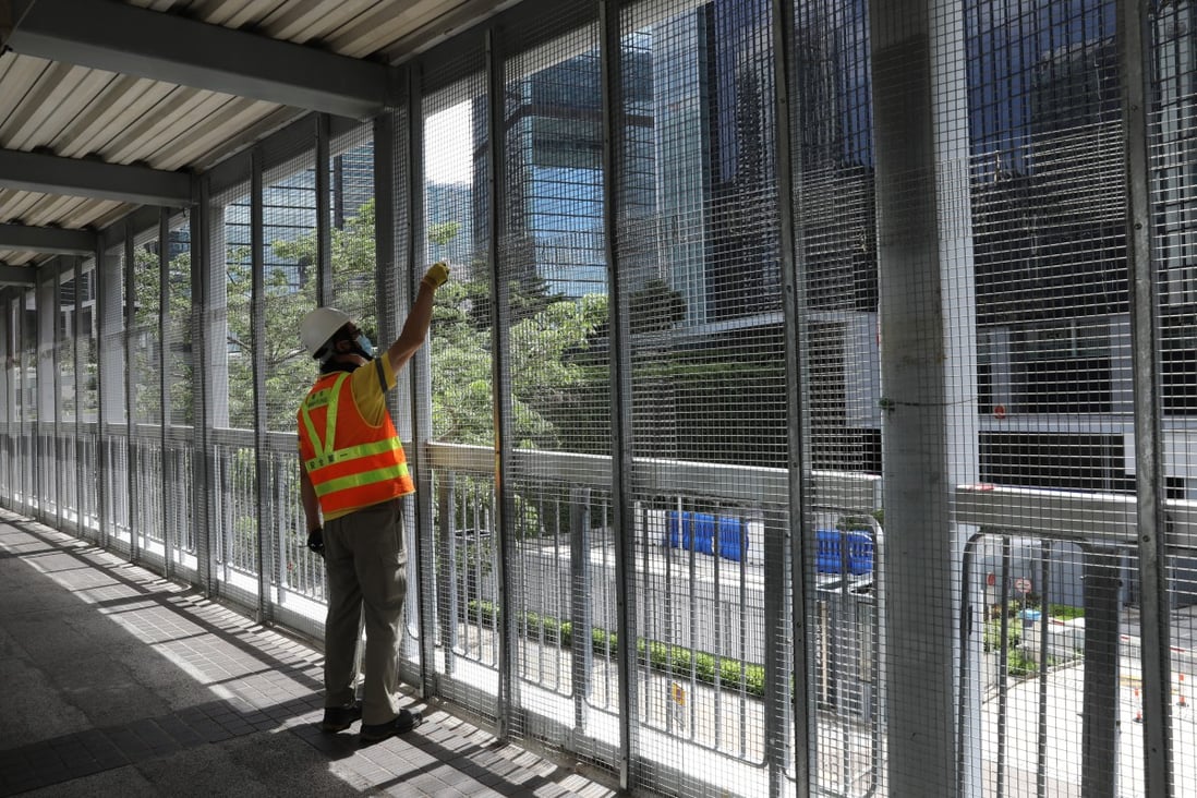 A worker checks the fence on a footbridge leading to the Legislative Council Complex in Tamar. Photo: Dickson Lee