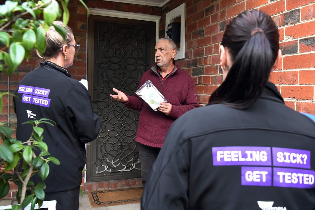 Health workers speak to a resident of the Melbourne suburb of Brunswick West as they encourage people to take coronavirus tests. Photo: AFP