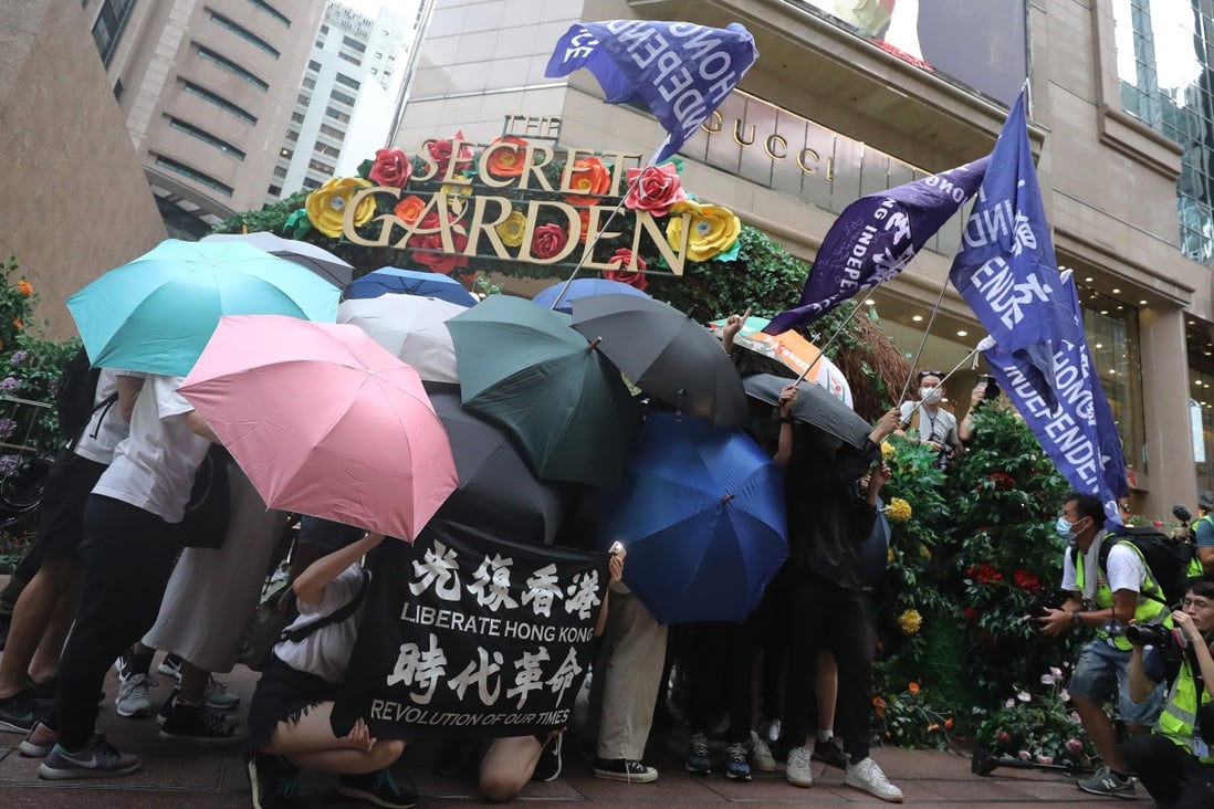 Anti-government protesters wave flags outside the Times Square shopping mall in Causeway Bay on July 1. Photo: May Tse