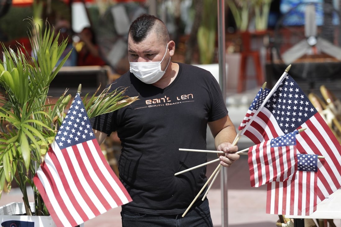 Marvin Turcios puts out American flags at Ocean's 10 restaurant on Miami Beach. Photo: AP Photo